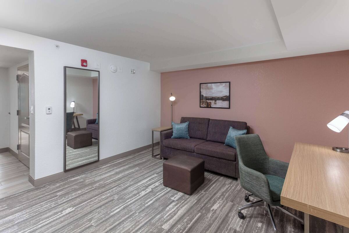 A modern room with a sofa, a small table, a chair, and a mirror.