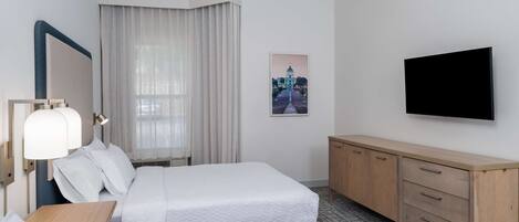 Een hotelkamer met twee bedden, een bureau, een spiegel, een televisie en een schilderij aan de muur.