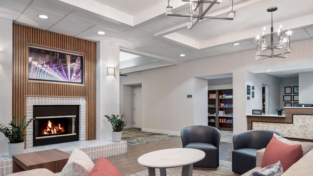 A modern lobby with a fireplace, comfortable seating, a television, and a reception area. - Homewood Suites by Hilton Montgomery (Montgomery)