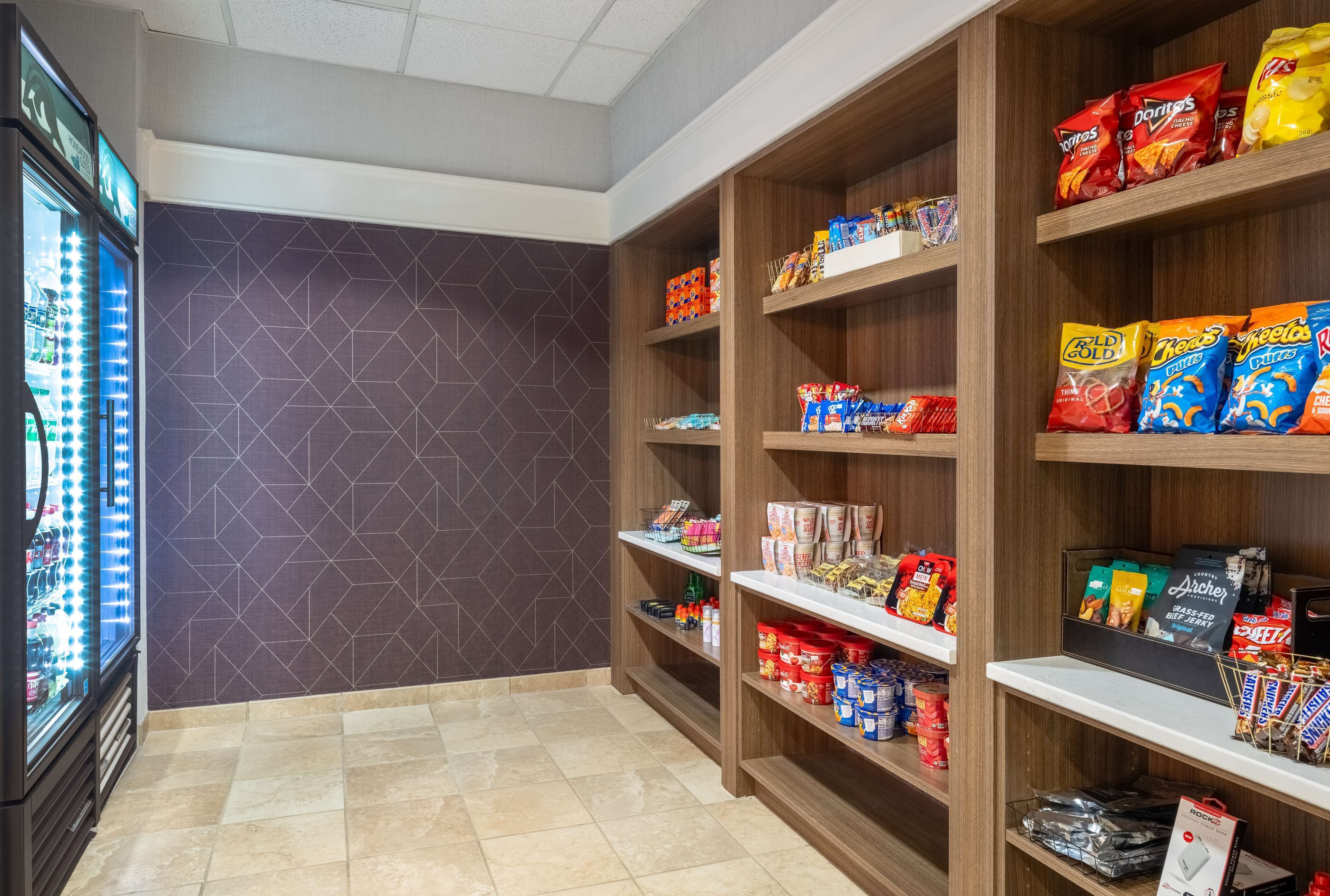 Un espace dédié aux collations, avec des étagères remplies de chips, de produits d’épicerie et de boissons.