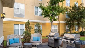 An outdoor patio with wicker chairs, a grill, and a table. - Homewood Suites by Hilton Montgomery (Montgomery)