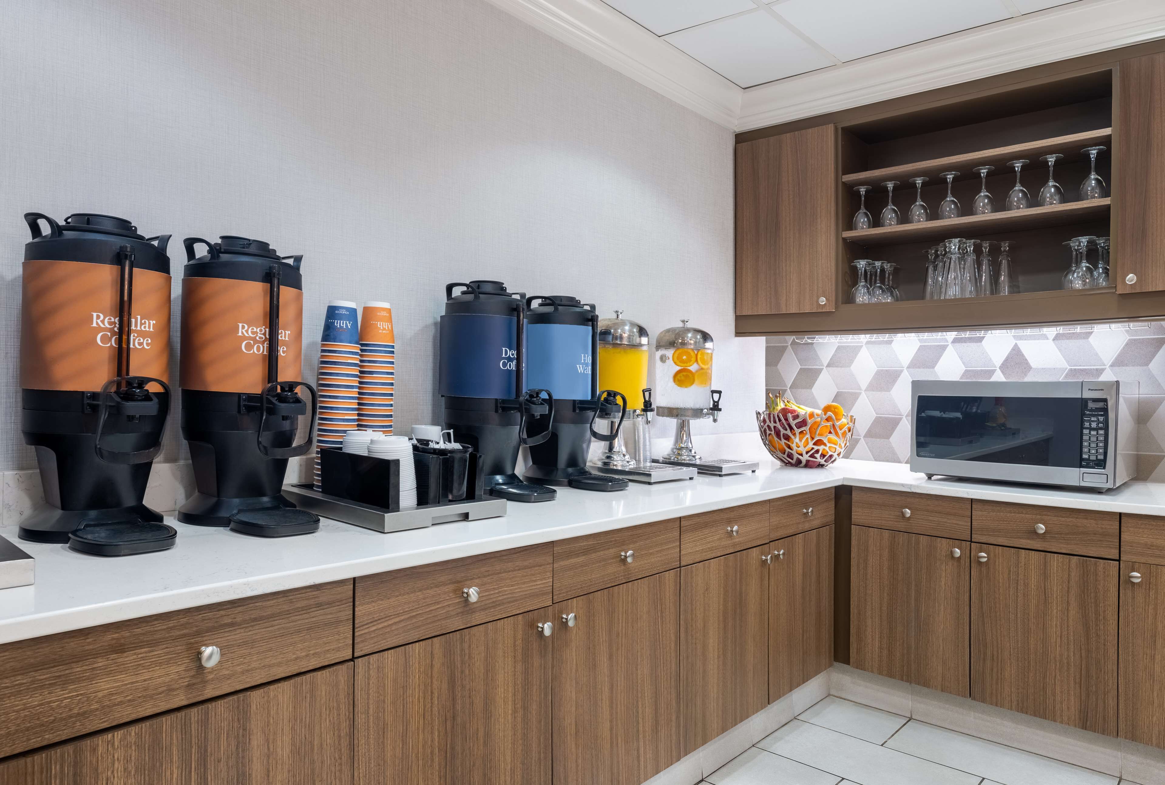 A modern kitchen with coffee makers, a microwave, and a glass display.