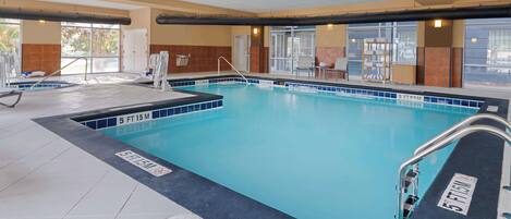 An indoor swimming pool with clear water, marked depth lines, and a tiled floor.