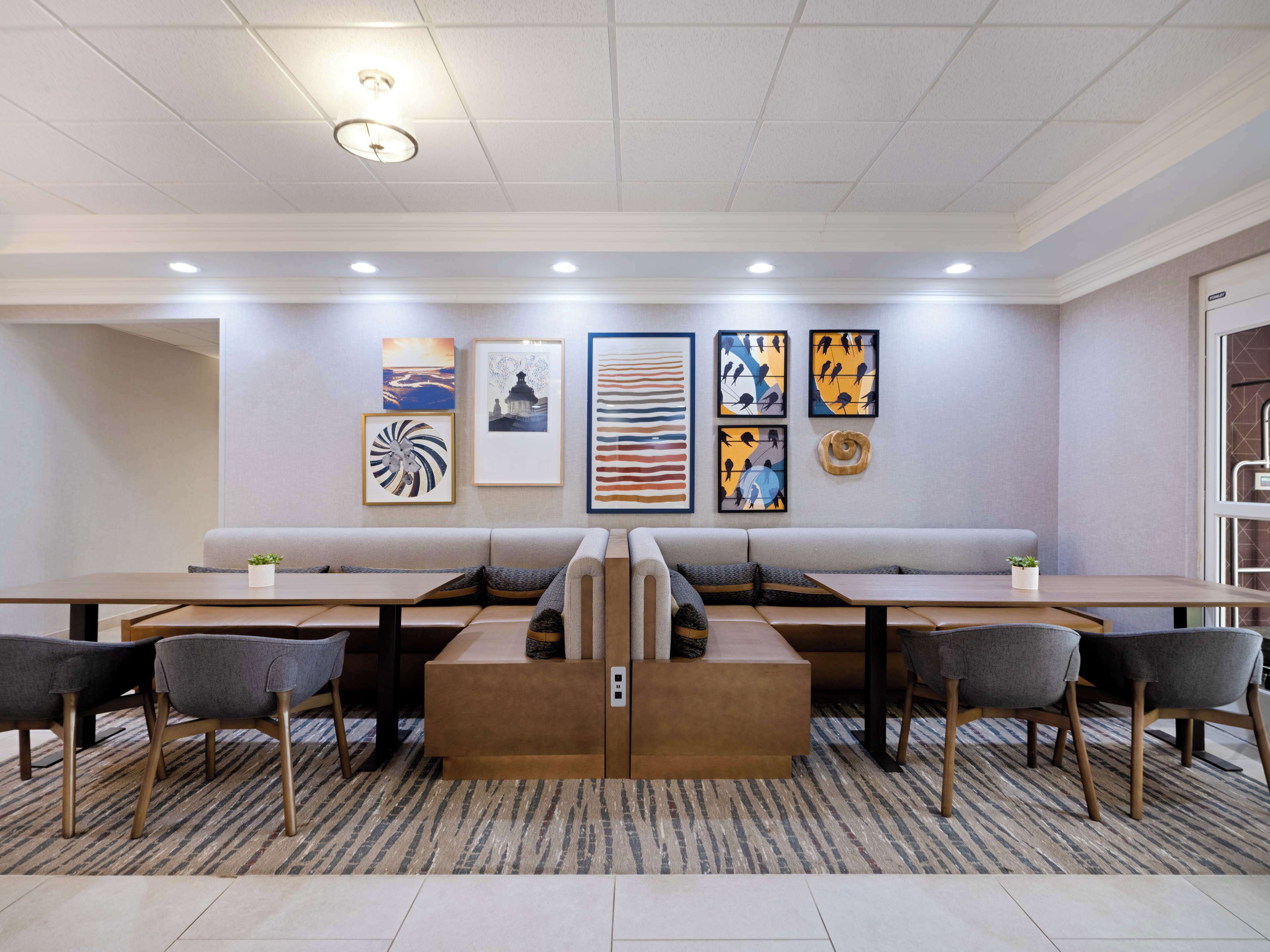 A modern lounge area with a long bench, multiple tables, and chairs.