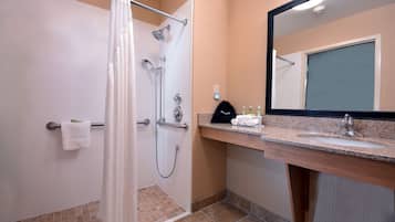 Un baño con ducha, lavamanos y espejo.