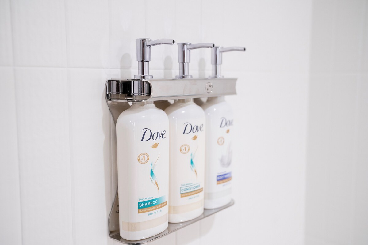 A bathroom with Dove shampoo and conditioner bottles on a shelf.