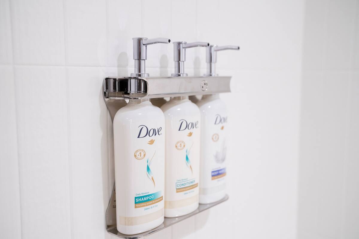 A bathroom shelf with Dove shampoo and conditioner bottles.
