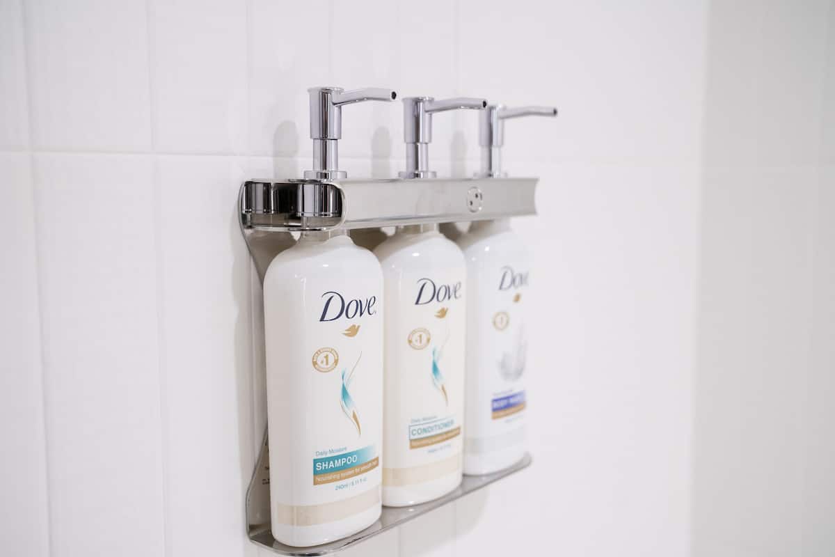 Un estante de baño con botellas de champú y acondicionador Dove.