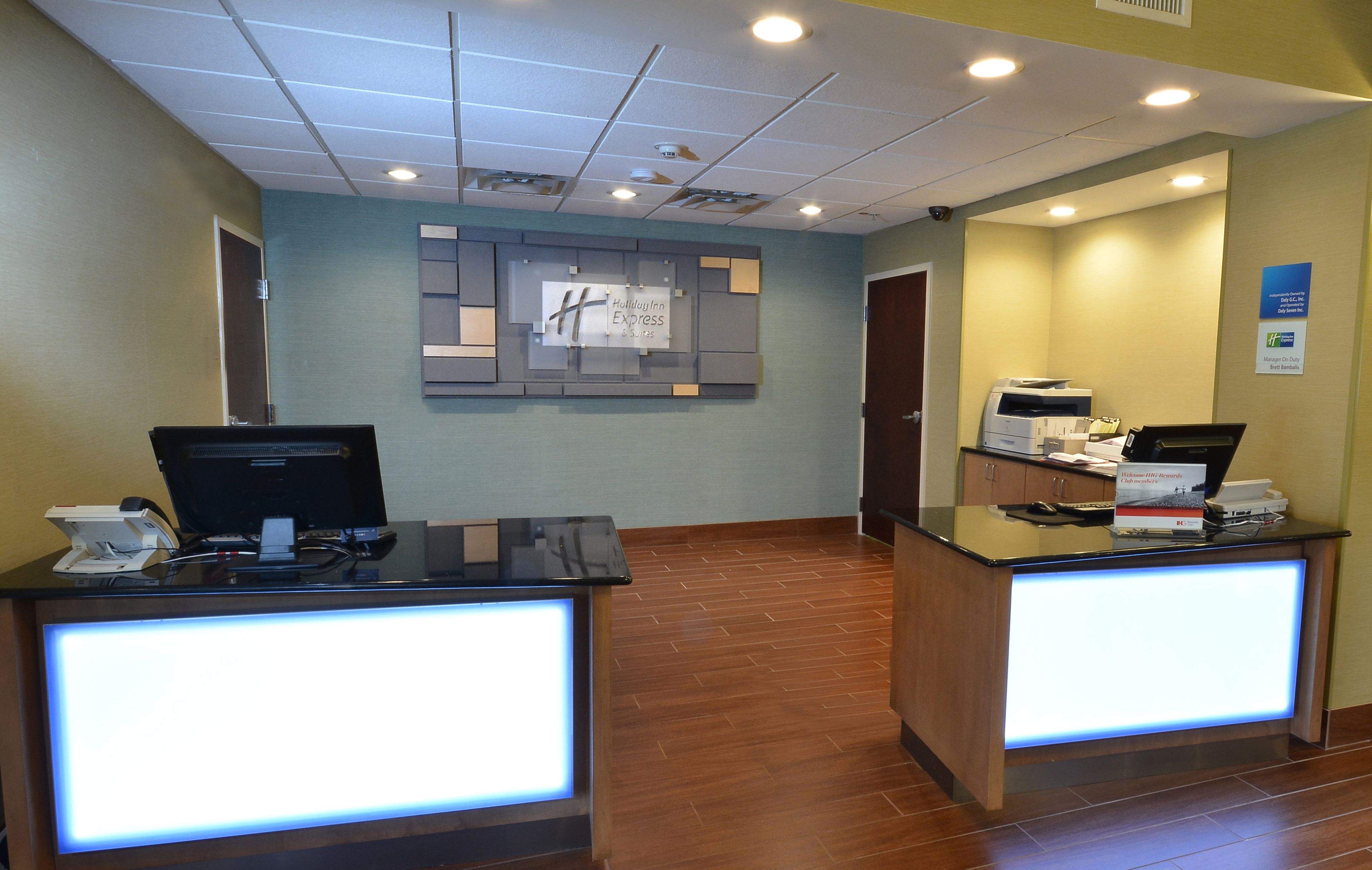 A hotel reception desk with a computer, a printer, and a sign indicating the hotel name.