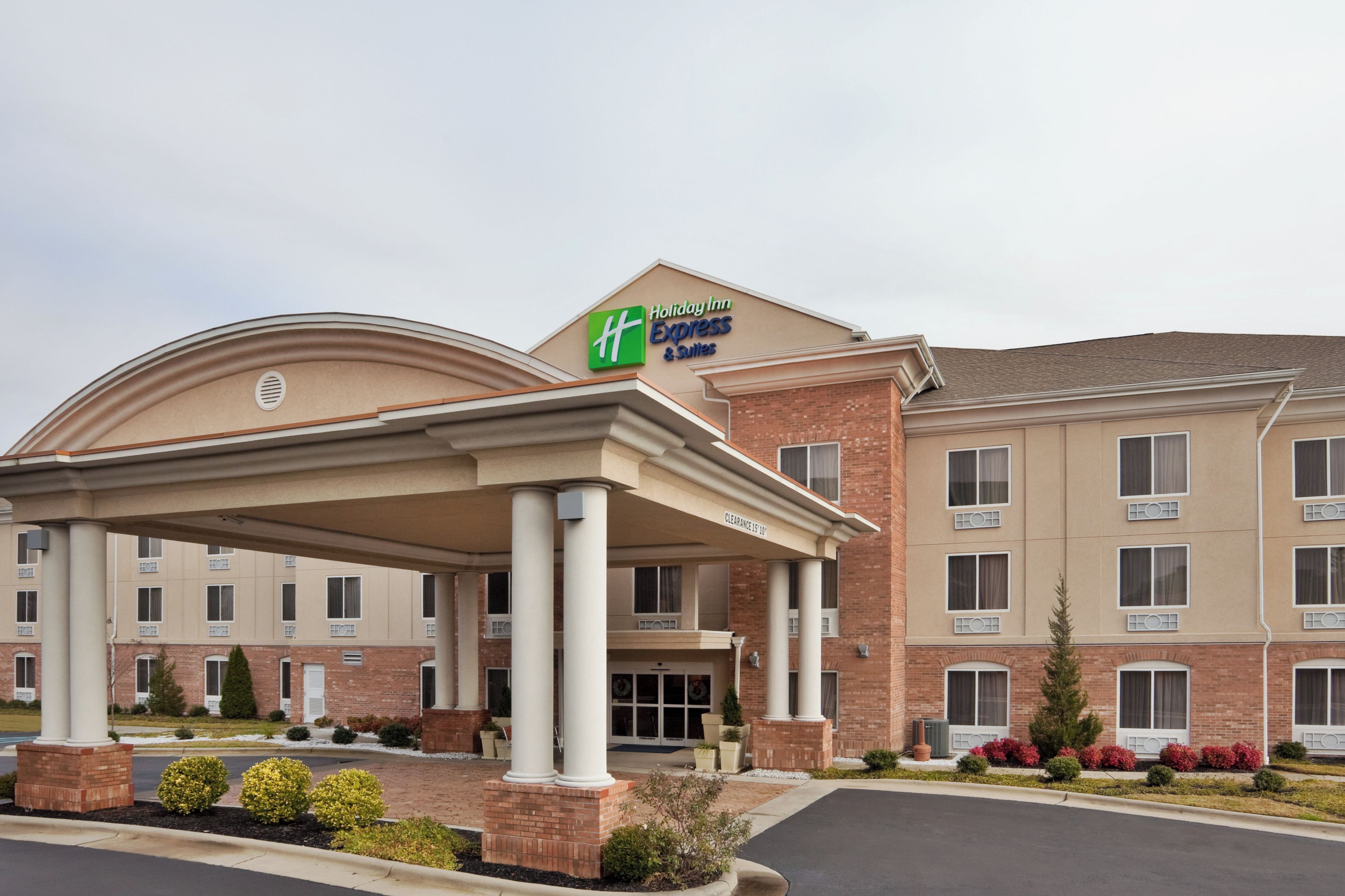 A Holiday Inn Express & Suites hotel with a covered entrance, brick facade, and multiple windows.