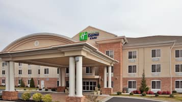 A Holiday Inn Express & Suites hotel with a covered entrance, brick facade, and multiple windows.