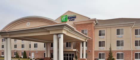 A Holiday Inn Express & Suites hotel with a covered entrance, brick facade, and multiple windows.