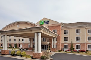 Un hotel Holiday Inn Express & Suites con entrada cubierta, fachada de ladrillo y varias ventanas.