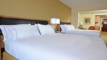 A hotel room with two large beds, a nightstand, a lamp, and a painting on the wall.