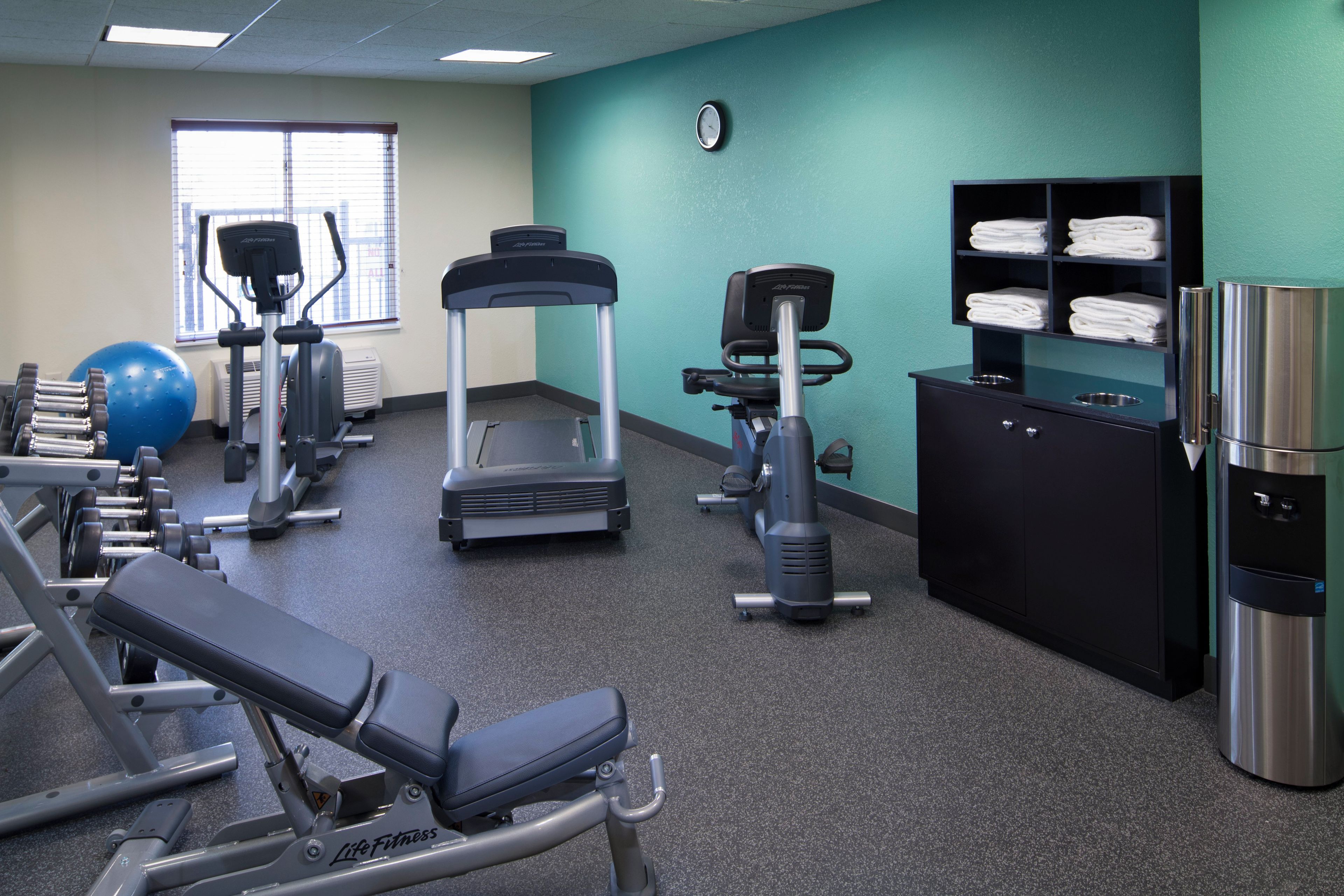 A gym with various exercise equipment, a water dispenser, and a towel rack.