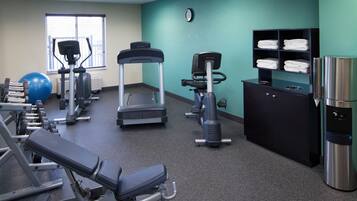 A gym with various exercise equipment, a water dispenser, and a towel rack.