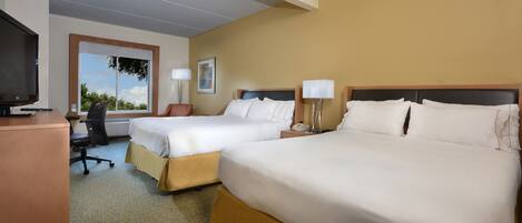 A hotel room with two beds, a desk, a TV, and a window with a view.