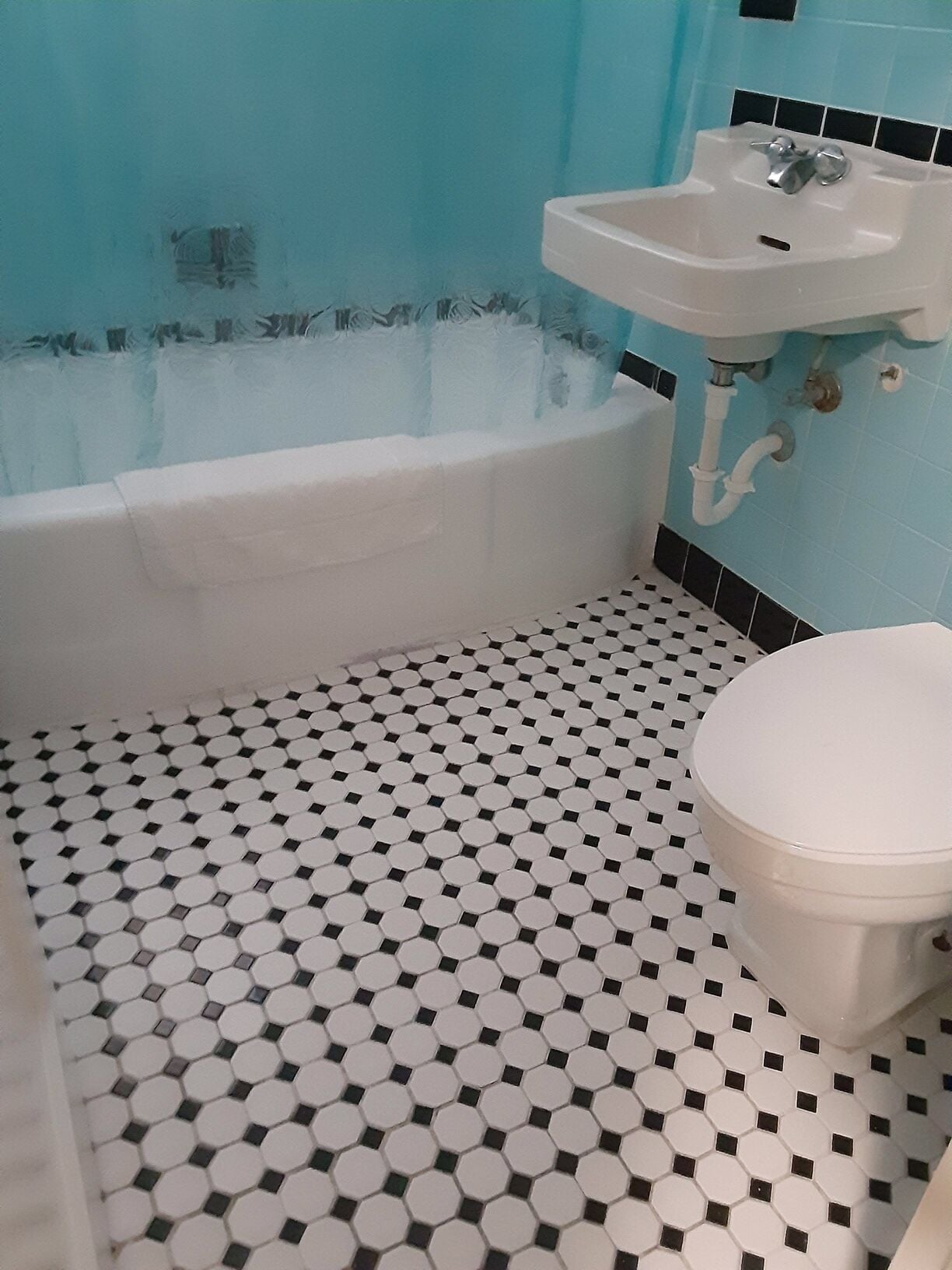 A bathroom with a bathtub, sink, toilet, and a tiled floor with a hexagonal pattern.