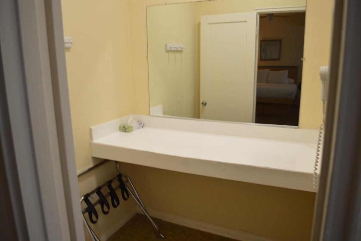 A bathroom with a white sink, a mirror, and a towel rack.