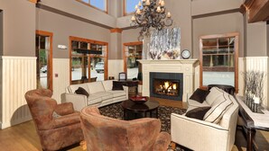 A spacious living room with a fireplace, leather armchairs, and a chandelier. - Main Street Junction (Breckenridge)