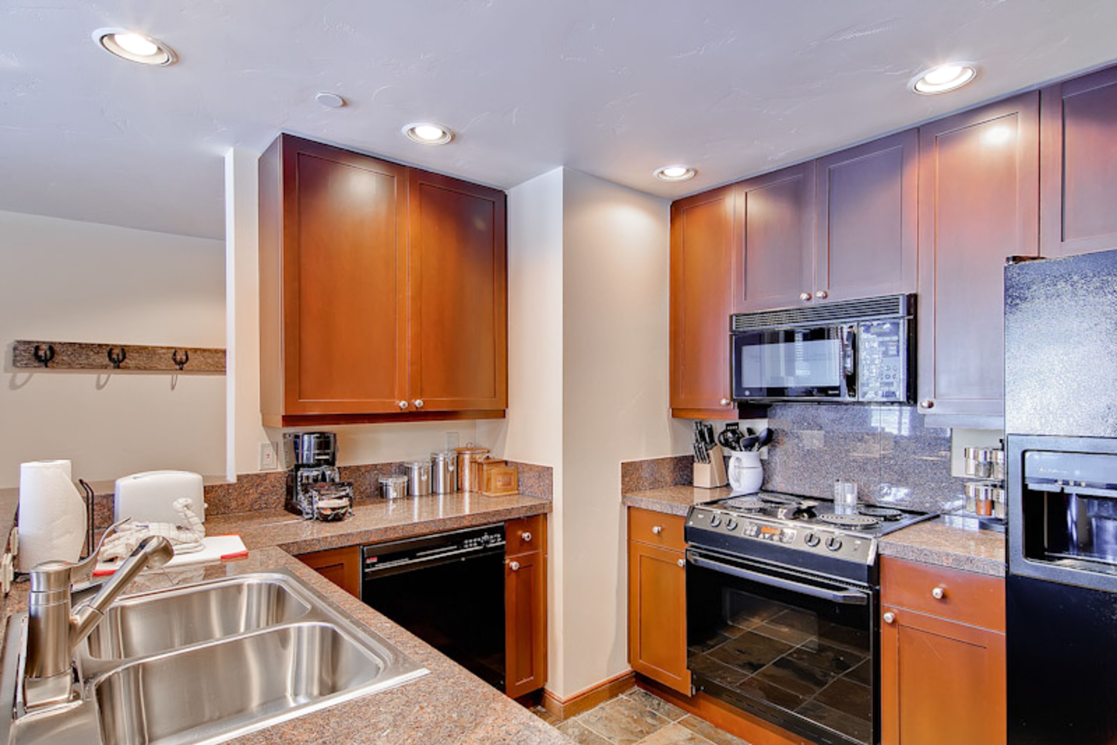 A modern kitchen with wooden cabinets, stainless steel appliances, and granite countertops.