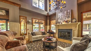 A spacious living room with leather sofas, a fireplace, and a large window overlooking a parking area. - Main Street Junction (Breckenridge)