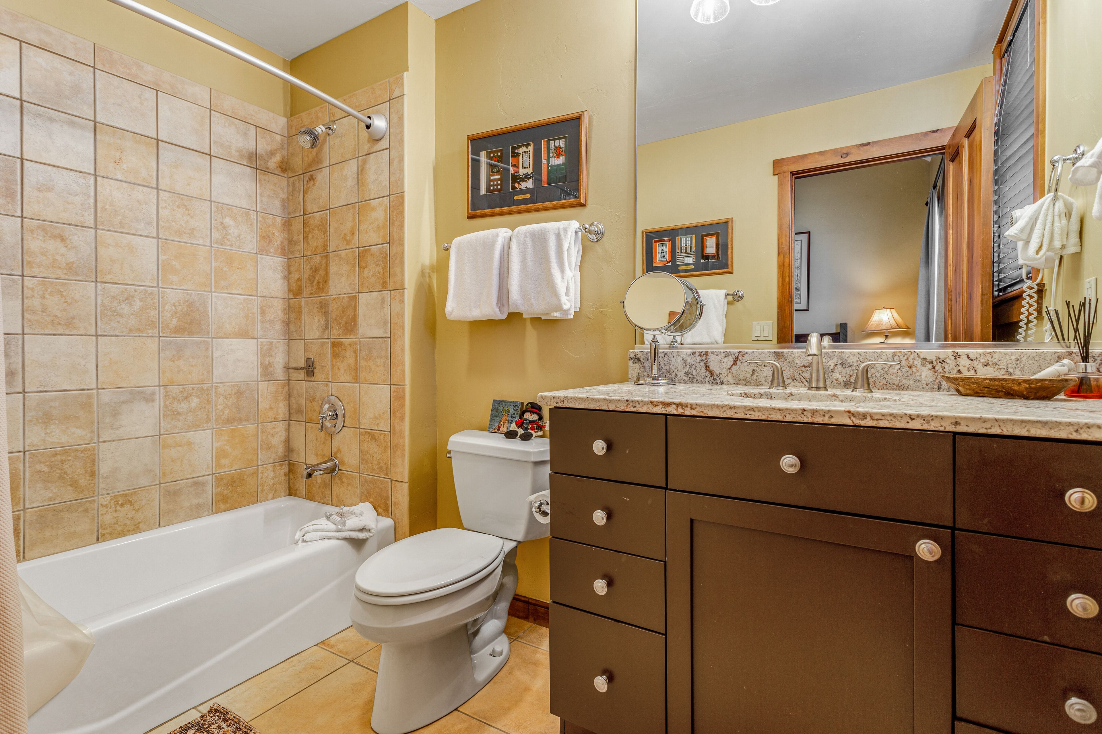 A bathroom with a bathtub, toilet, vanity with drawers, and a mirror.