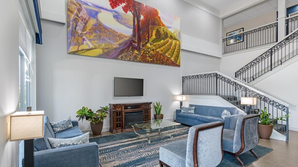 A spacious living room with a large painting, a fireplace, a staircase, and modern furniture. - Best Western Plus Washington Hotel (Washington)
