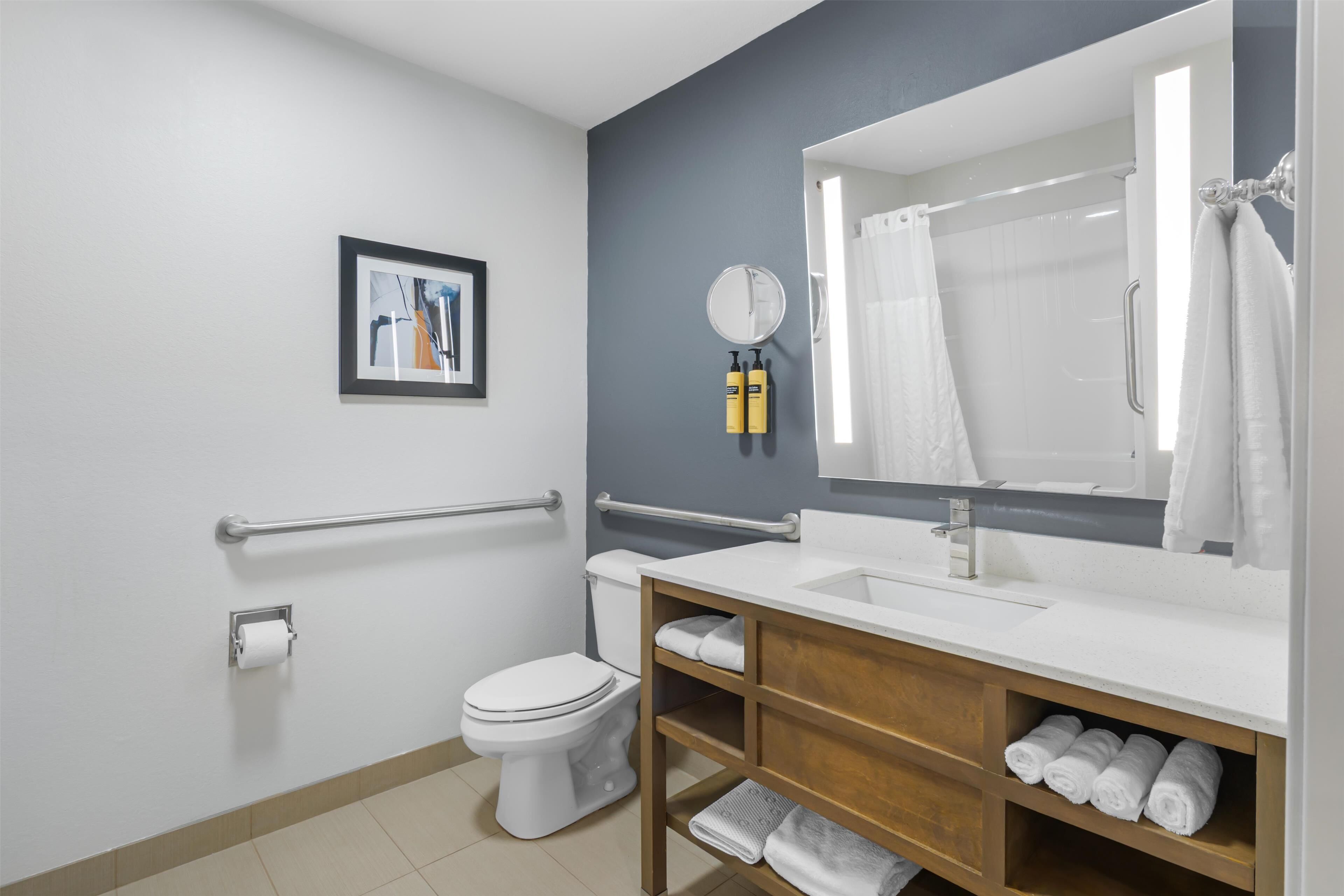 A modern bathroom with a white toilet, a sink with a mirror, and a shower area.