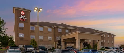 A Best Western Plus hotel with a parking lot filled with various cars.