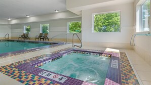 A swimming pool with tiled edges and a hot tub area, surrounded by windows and chairs. - Best Western Plus Washington Hotel (Washington)