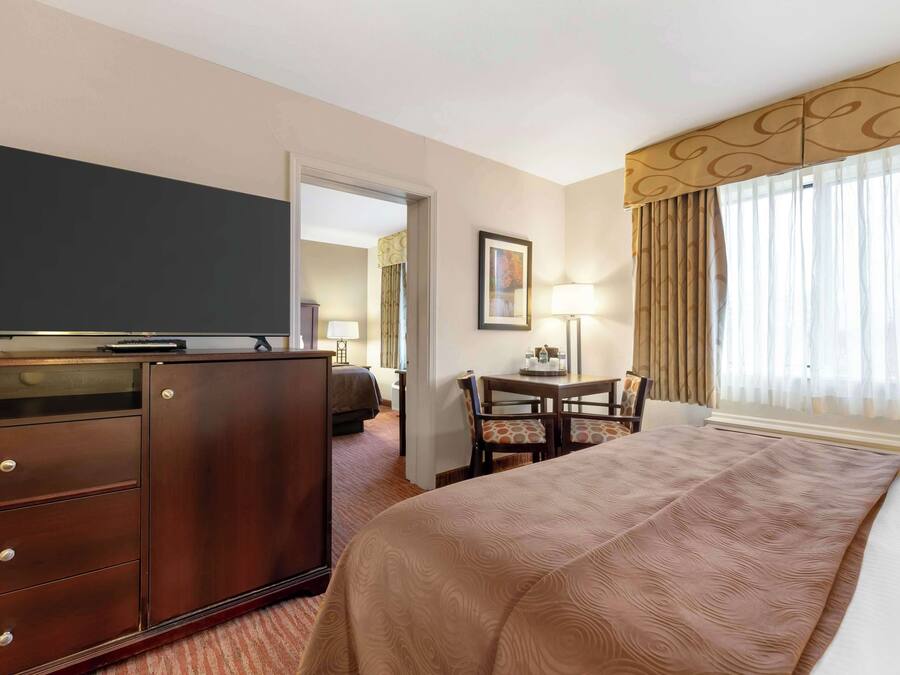 A hotel room with a bed, a desk, a dresser, and a television.