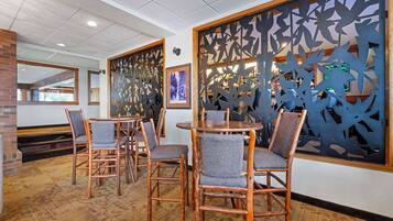Un restaurante con sillas y mesas de madera, un muro de ladrillo y paneles decorativos.