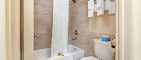 Un baño con bañera, inodoro y toallero.