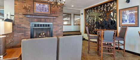 A cozy interior with a fireplace, cushioned seating, and wooden chairs.