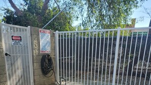 A swimming pool with a metal ladder, surrounded by a white fence and a spa rules sign. - Signature Hotel by Tachi (Hanford)