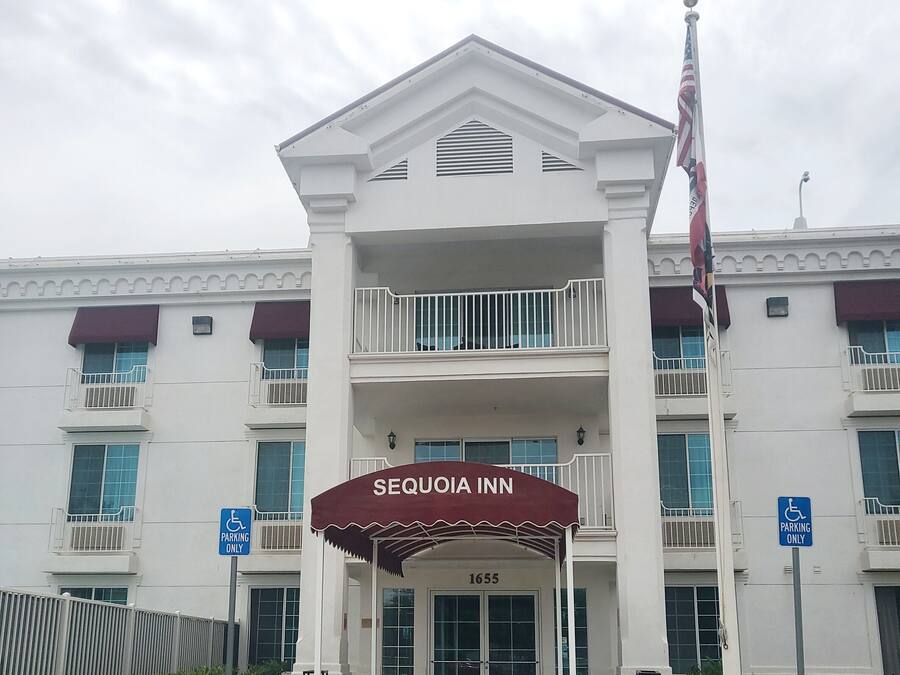 A hotel entrance with a covered area, a flag, and handicap parking signs.