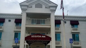 A hotel entrance with a sign reading "SEQUOIA INN" and a handicap parking sign.