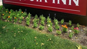 A sign for Sequoia Inn with a red background and white lettering. - Signature Hotel by Tachi (Hanford)