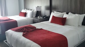 A hotel room with two beds, a nightstand, a lamp, and a ceiling light.