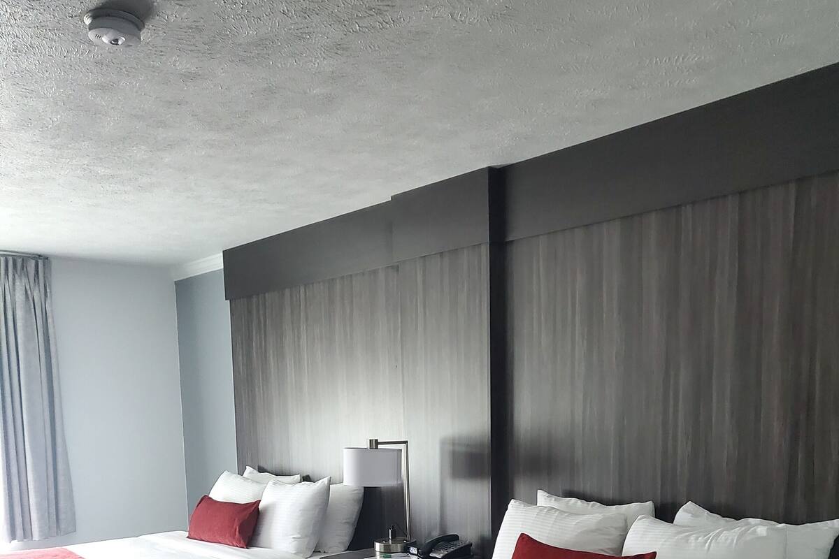 Una habitación de hotel con dos camas, una mesita de noche, una lámpara y una luz en el techo.