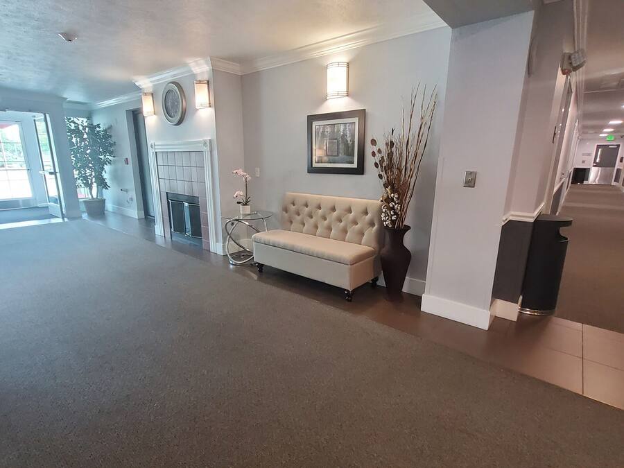 A spacious living area with a beige sofa, a fireplace, and a wall-mounted picture.