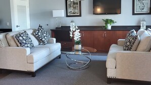 A living room with two sofas, a coffee table, a TV, and a cabinet. - Signature Hotel by Tachi (Hanford)