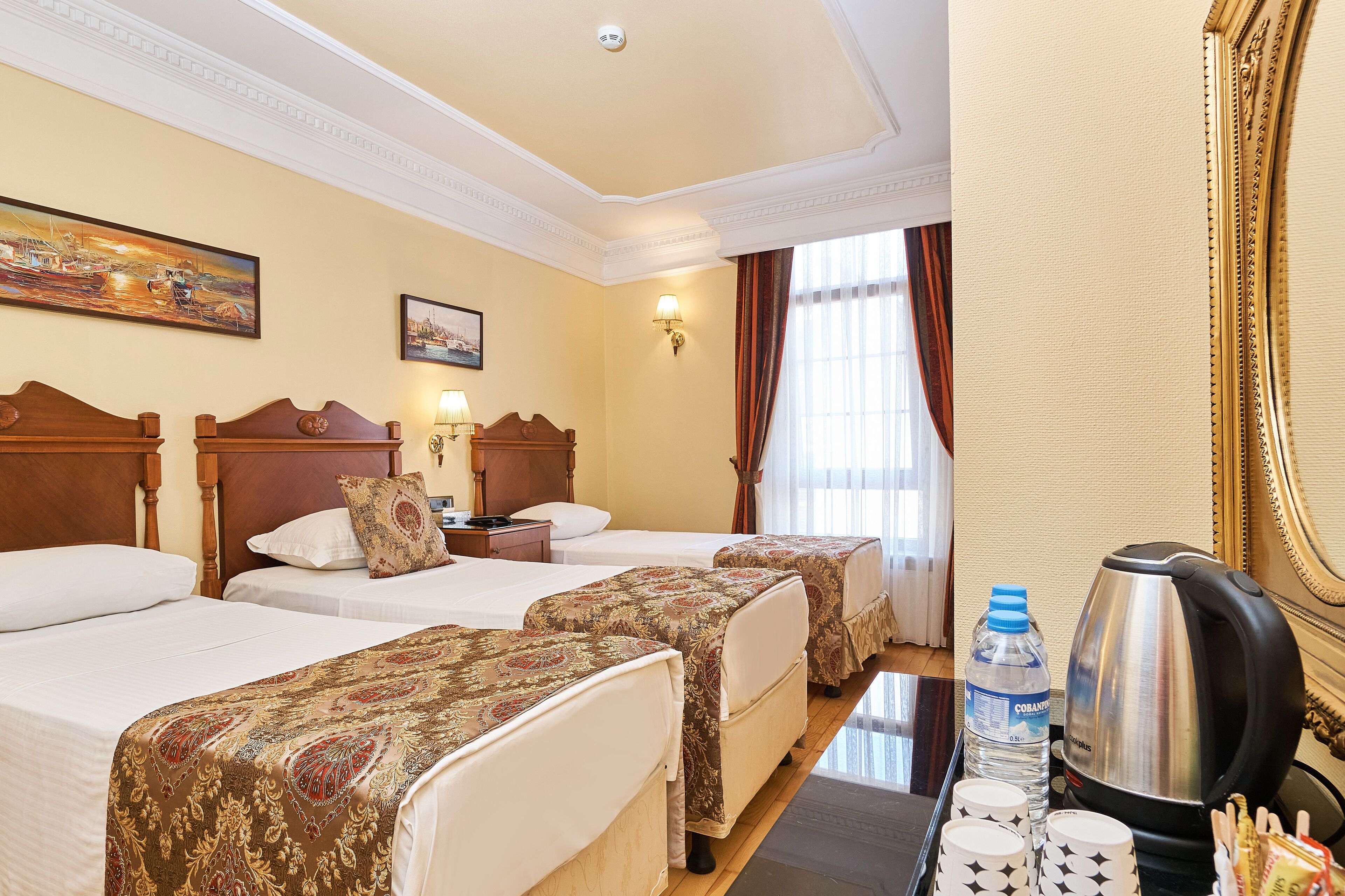 A hotel room with two beds, a coffee maker, a water bottle, and a tray with cups.
