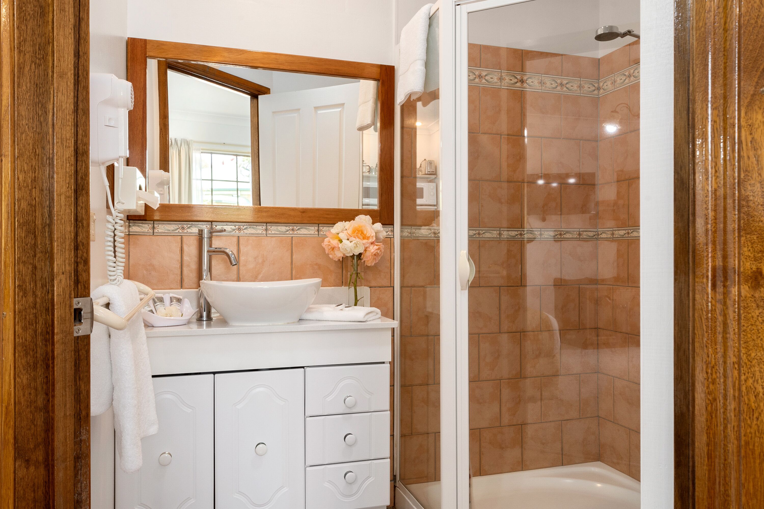 A bathroom with a white sink, a mirror, a hairdryer, and a shower.