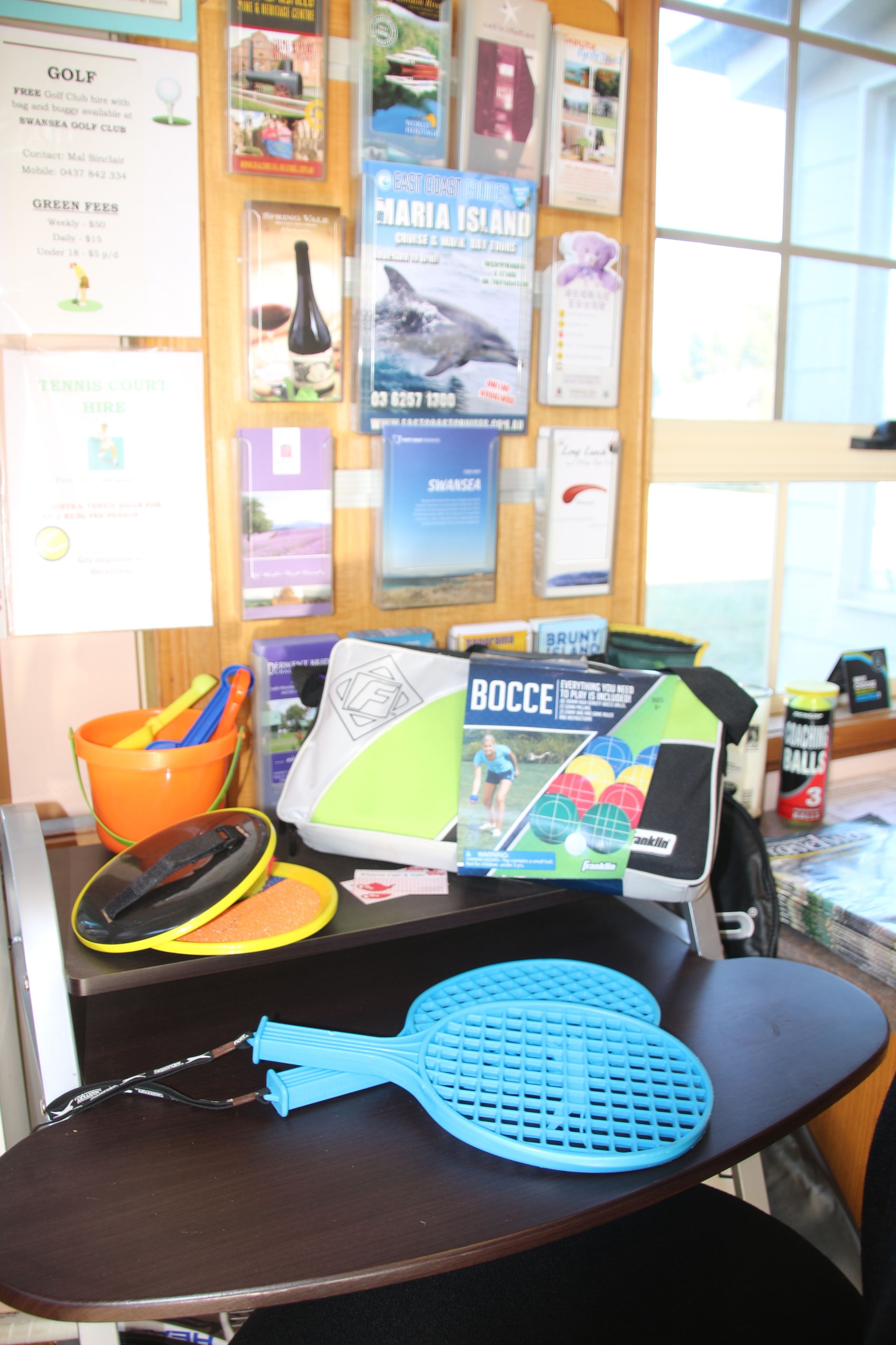 A table with a blue tennis racket, a green and black bocce ball, and a yellow and black tennis ball.