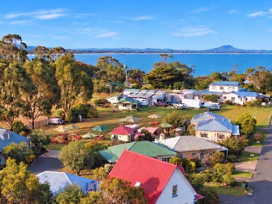 A coastal residential area with houses, a clear sky, and a view of the sea.
