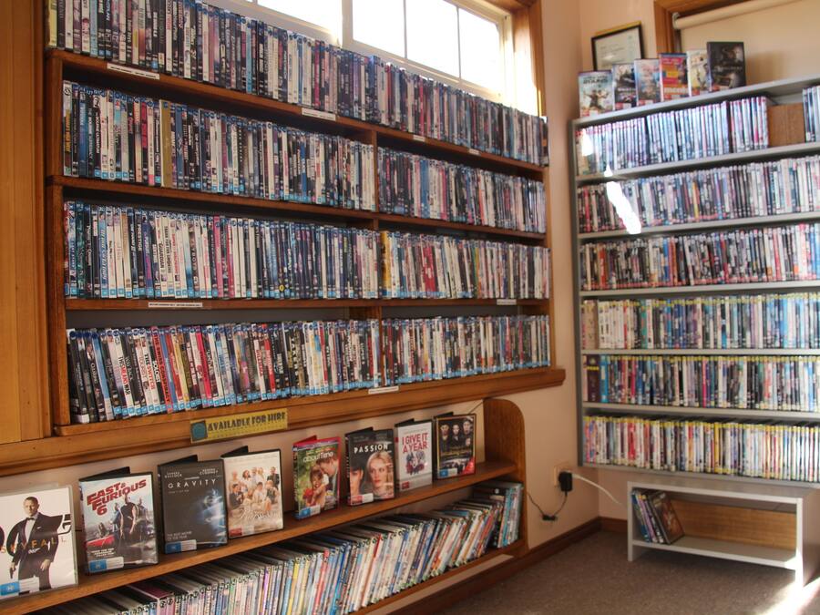 A library with multiple shelves of DVDs and books.
