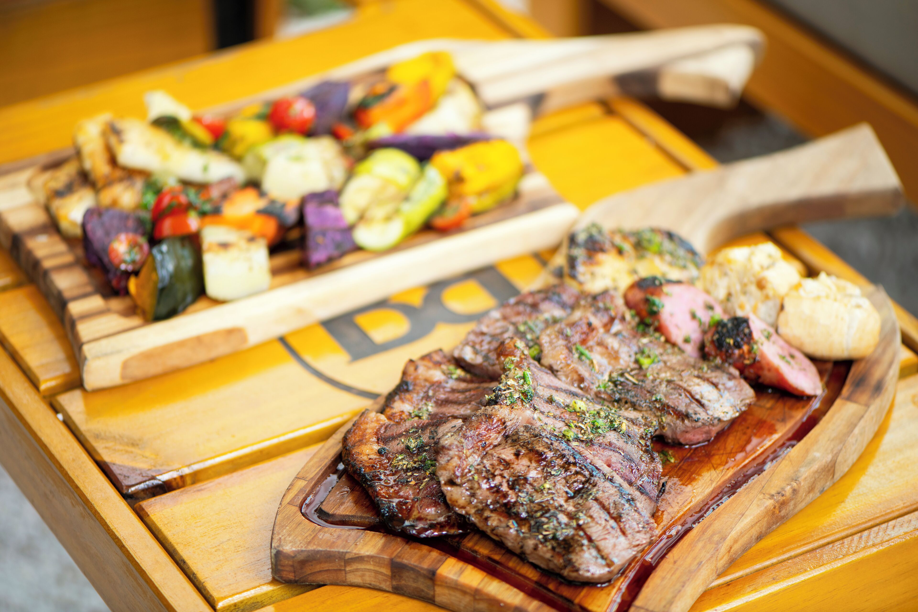 A wooden table with a variety of grilled meats and vegetables.