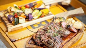 A wooden table with a variety of grilled meats and vegetables.